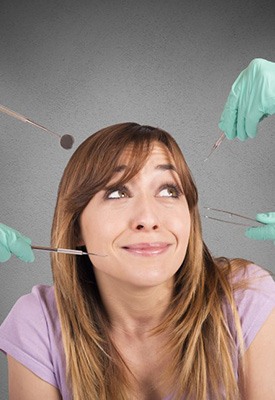 Woman looking nervously at multiple dental tools